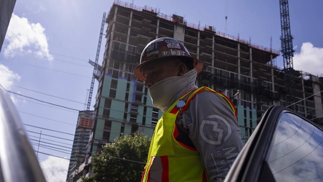 Construction worker Martin Capallera, 50, puts on his neon vest and neck gaiter after taking a break in his car to escape the late-morning heat in Austin’s West Campus neighborhood on July 6. Capallera specializes in rewiring buildings and currently works on the 24th floor of a new building. “We try to keep our people safe,” Capallera said. “We’re all the time under the sun.” - Texas Tribune / Joe Timmerman