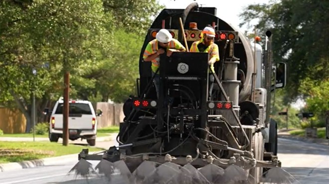 A truck sprays cool pavement, which is a reflective material that reduces the amount of heat absorbed by the pavement.