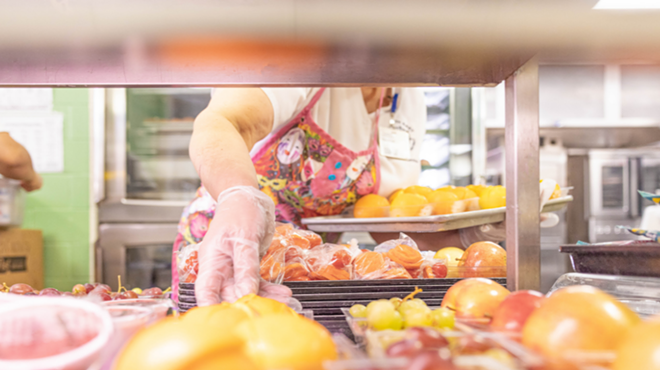 A North East ISD cafeteria employee arranges fruit on a tray.