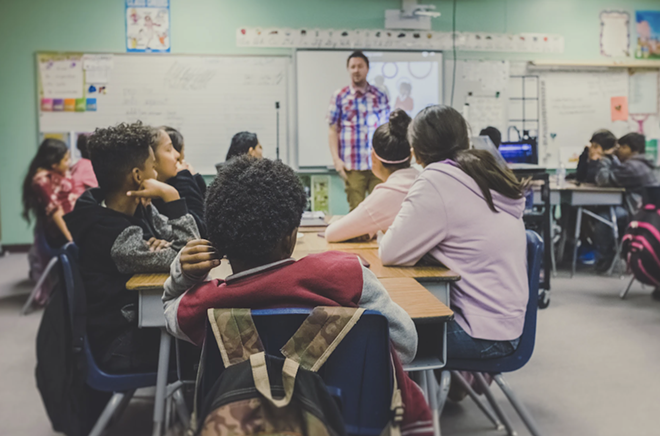 A teacher speaks to a room full of students. - Unsplash / Kenny Eliason