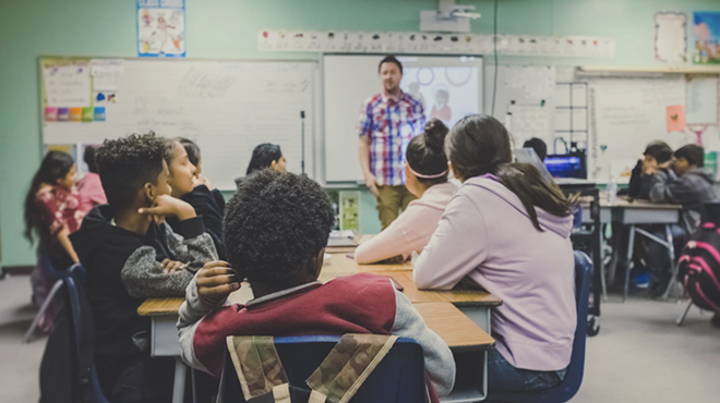 A teacher speaks to a room full of students.